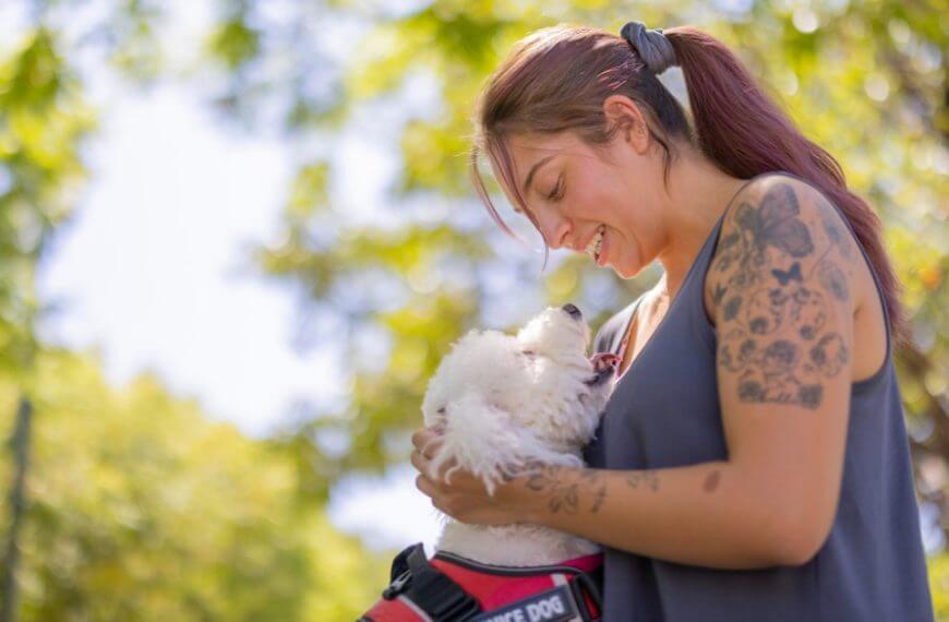 We have a remarkable lady here; donning a vivid artwork of tattoos, exuding strength and self-assurance that's nothing short of admirable. And there, by her side, a faithful companion - an angelic white dog. These are the resilient underdogs who thrive in life’s symphony despite its challenging rhythm—heroes for our hard-of-hearing youth to look up to.