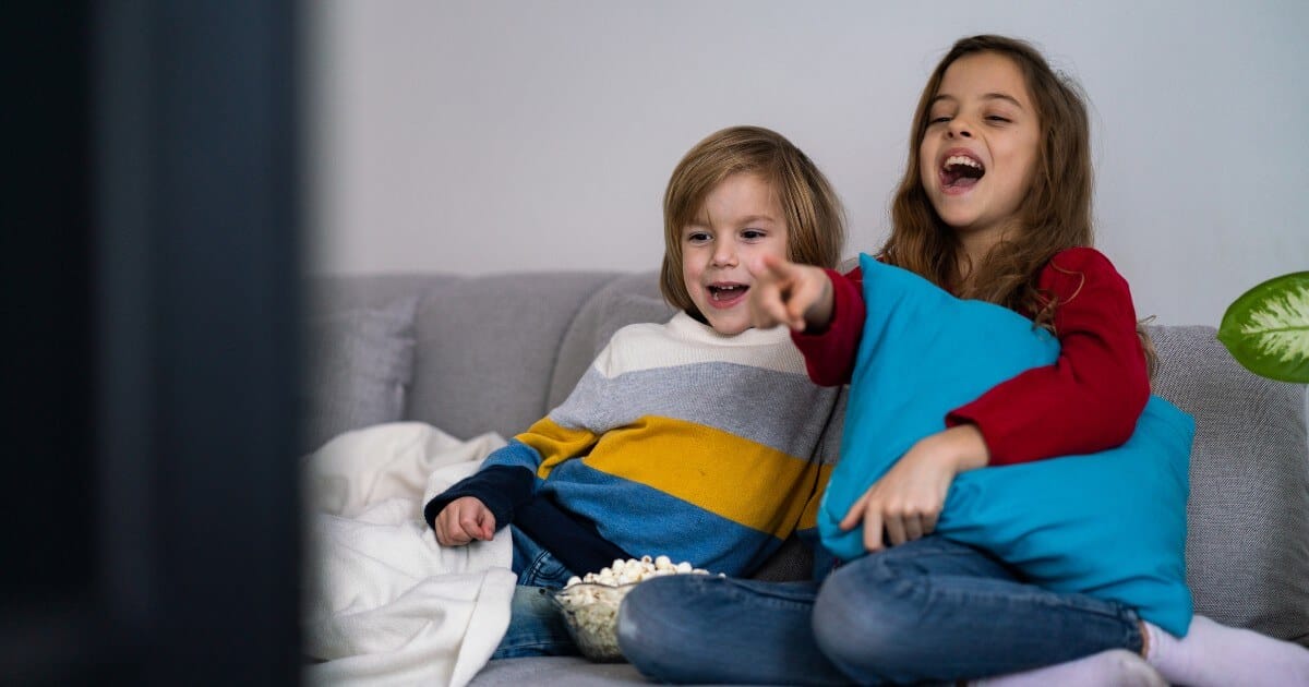 In our ever-evolving technological world, a panoramic spectrum of possibility brightly waits on the comforts of two young souls, seated side by side on a cozy couch. The mesmerizing glow from the television engrosses their entirety - painting vivid images of empowerment and inspiration upon the canvas that is their curious minds. This extraordinary sight underlines that monumental truth: even in youth with hearing ambitions defined differently, potential unfurls with boundless vigor.