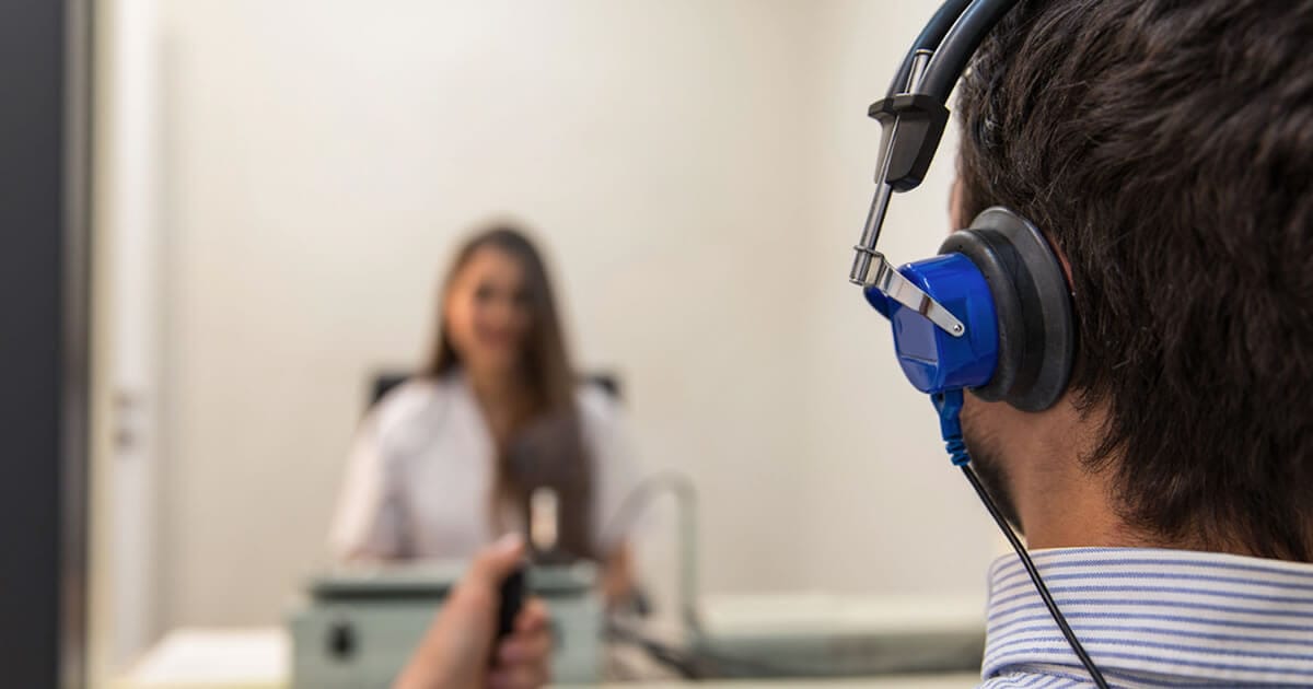Picture this: a young individual with headphones securely over their ears, holding a sleek electronic device. They sit face-to-face with a specialist conducting an intricate hearing test within the calm confines of a soundproof room. The setting is straightforward and clinical, featuring the examiner stationed behind an array of specialized equipment on their desk.

At [Foundation’s Name], we're dedicated to transforming these clinical encounters into empowering moments for hard-of-hearing youth. Through cutting-edge auditory assessments and personalized support, we don't just measure hearing – we unlock potential and pave pathways to brighter futures.