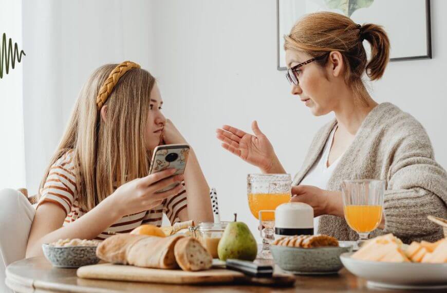 A mother and daughter sitting at a breakfast table, engaged in a meaningful conversation about confidence and support.