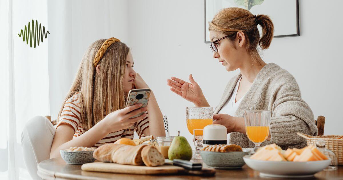 A mother and daughter sitting at a breakfast table, engaged in a meaningful conversation about confidence and support.