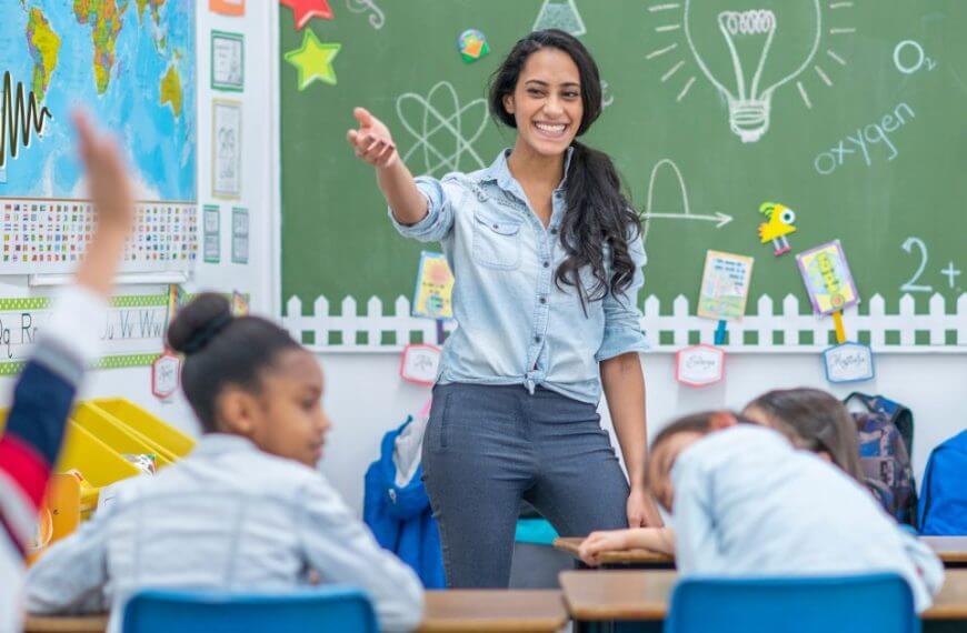 A smiling teacher engaging with students in a classroom, demonstrating the importance of clear communication for hard-of-hearing students using microphone systems.
