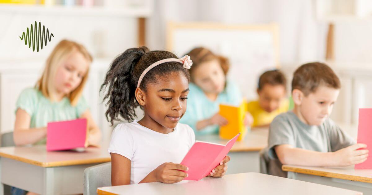A diverse group of young students in a bright classroom, reading colorful booklets. The classroom fosters inclusion, with a focus on supporting hard-of-hearing students through clear communication and an engaging learning environment.